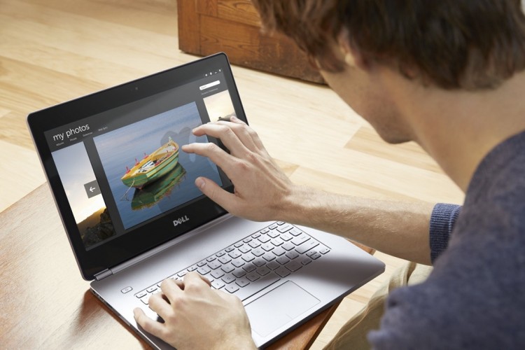 Man using Dell Inspiron 14 (7437) Touch notebook computer seated on a floor cushion at a low coffee table in a minimalist living room.